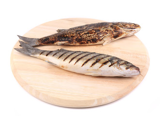Two grilled seabass fish on platter.