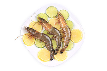 Raw shrimps on plate with lemon and lime.