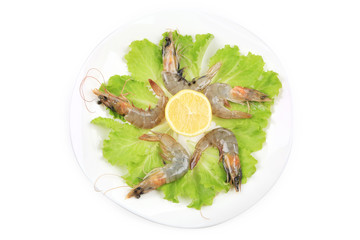Raw shrimps on plate with lettuce and lemon.