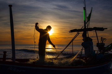 silhouette of fisherman with sunrise in the background