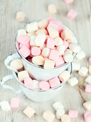 marshmallows in metallic cups on wooden table