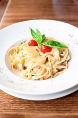 Fettuccine pasta with cream sauce and bacon. Indoors closeup.