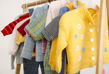 Wardrobe of newborn with clothes arranged on hangers toys