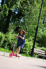 Happy girl riding a scooter in a park