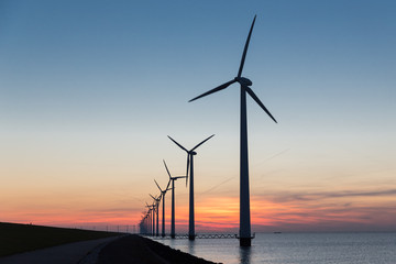 Dutch row offshore wind turbines at beautiful sunset
