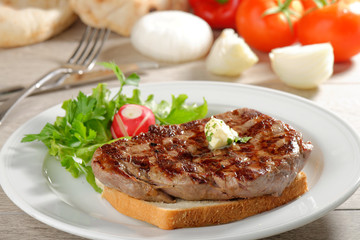 Grilled steak on toast bread, served with onion and vegetable