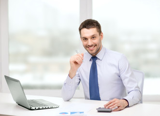 smiling businessman with laptop and documents