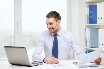 Fototapeta na wymiar smiling businessman with laptop and documents