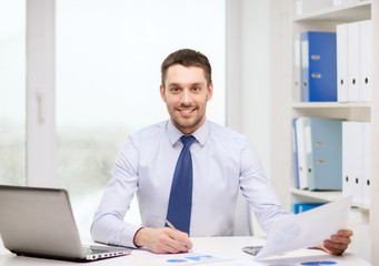 smiling businessman with laptop and documents