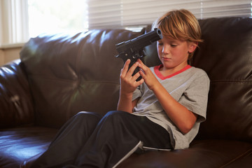Boy Playing With Parent's Gun He Has Found At Home