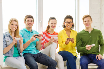 smiling students with smartphone texting at school