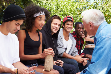 Senior Man Talking With Gang Of Young People