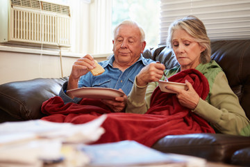 Obraz premium Senior Couple With Poor Diet Keeping Warm Under Blanket