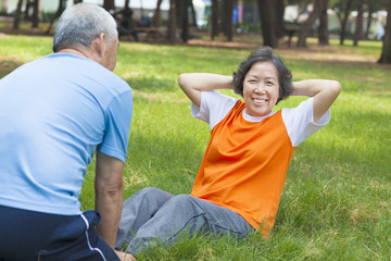 Naklejka premium smiling senior grandmother doing sit-ups in the park