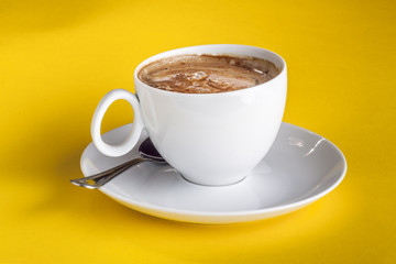 Coffee cup and saucer on a yellow background.