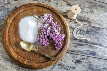 Lilac flowers and sugar on a wooden board