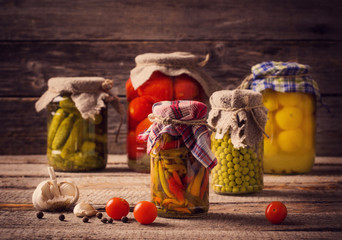 Preserved and fresh vegetables on wooden background