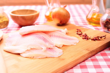 Raw fish tilapia on cutting board and spices