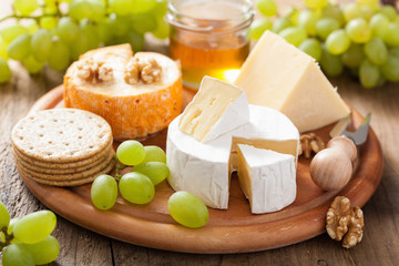 Fototapeta cheese plate with camembert, cheddar, grapes and honey obraz