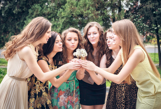 Group of College Girls Blowing Dandelion Seeds