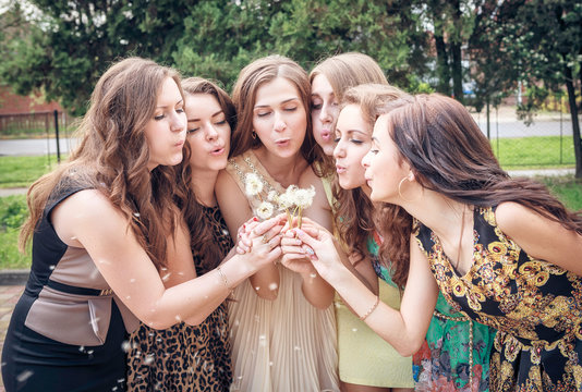 Group of College Girls Blowing Dandelion Seeds