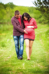 Fototapeta premium Young man with his pregnant wife on open air