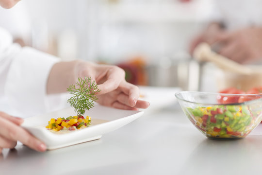 closeup on chef's hands garnishing a plate