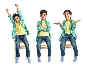 Obraz premium Happy brunette kid on wooden chair over white