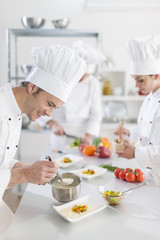  chef preparing a dish his team in the background