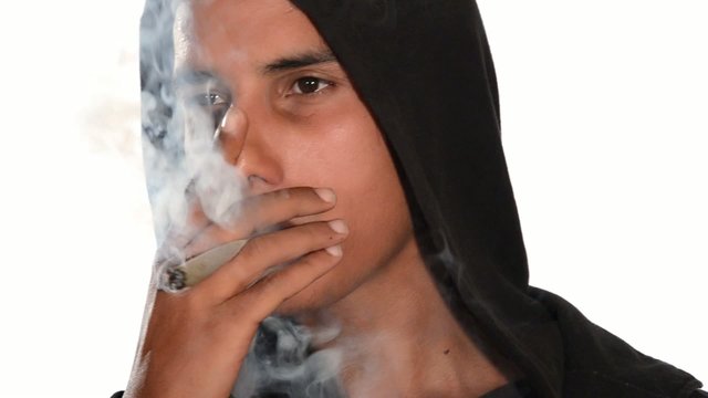 close up of young man smoking hashish joint on white background.