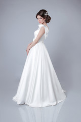 Fototapeta na wymiar Fashion bride woman posing in wedding dress isolated on gray bac