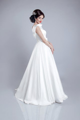 Fototapeta na wymiar Fashionable bride model in wedding dress isolated on gray backgr