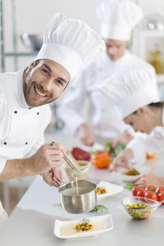  chef preparing a dish his team in the background