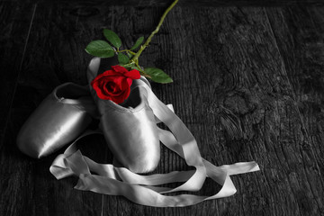 Old used ballet slippers lying on floor with rose on wood floor © Alta Oosthuizen