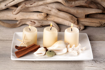 Obraz na płótnie Canvas Plate decoration with candles Shells Starfish Coral wood