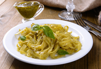 Delicious pasta with pesto on plate on table close-up