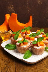 Tasty pumpkin muffins on wooden table