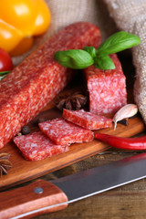 Tasty salami sausage and spices on wooden background