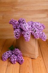 Beautiful lilac flowers in package on table on wooden