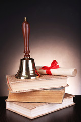 Obraz na płótnie Canvas Złota retro szkoła dzwon z książek na stole w ciemnym tle