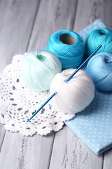 Colorful clews, napkin and crochet hook on wooden background