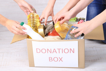 People makes foodstuffs out of donation box on grey background