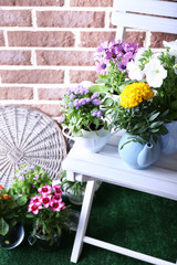 Fototapeta na wymiar Flowers in decorative pots on chair, on bricks background