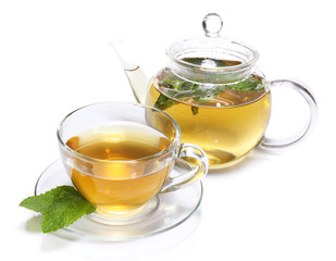 Composition of fresh mint tea in glass cup and teapot and brown