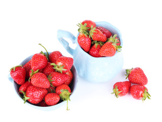 Ripe sweet strawberries in color mugs isolated on white