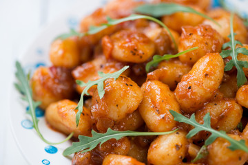Close-up of boiled gnocchi with tomato sauce and arugula