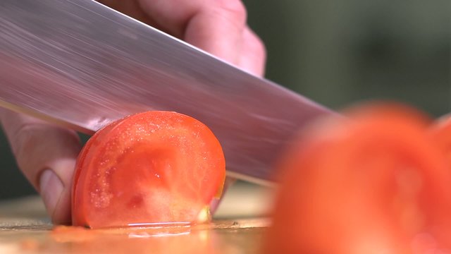Slicing tomato for salad with grilled vegetables