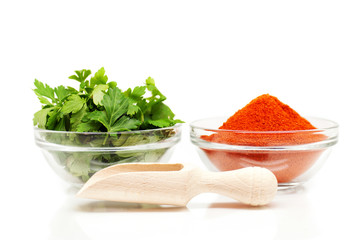 Parsley and ground red pepper with wooden spoon over white