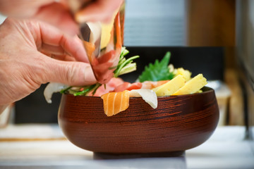 Hands of a Japanese Chef make a bowl of Sushi