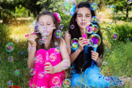 Portrait of two girls playing with bubble blower